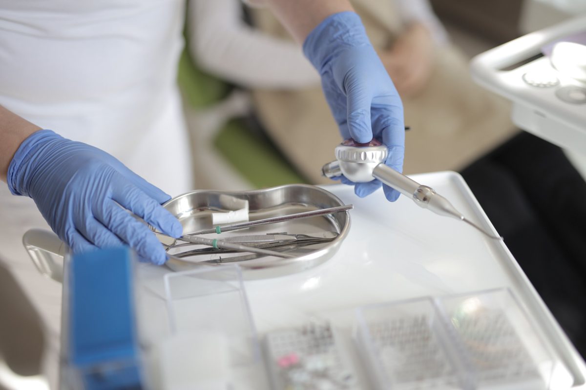 Gloved hands preparing a tray of dental instruments